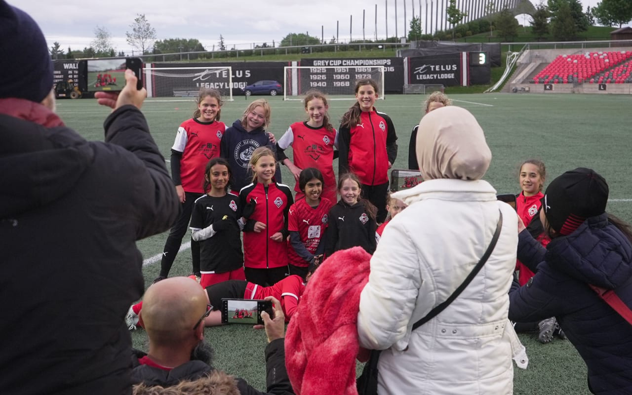 Parents taking pictures of a kids soccer team at TD Place