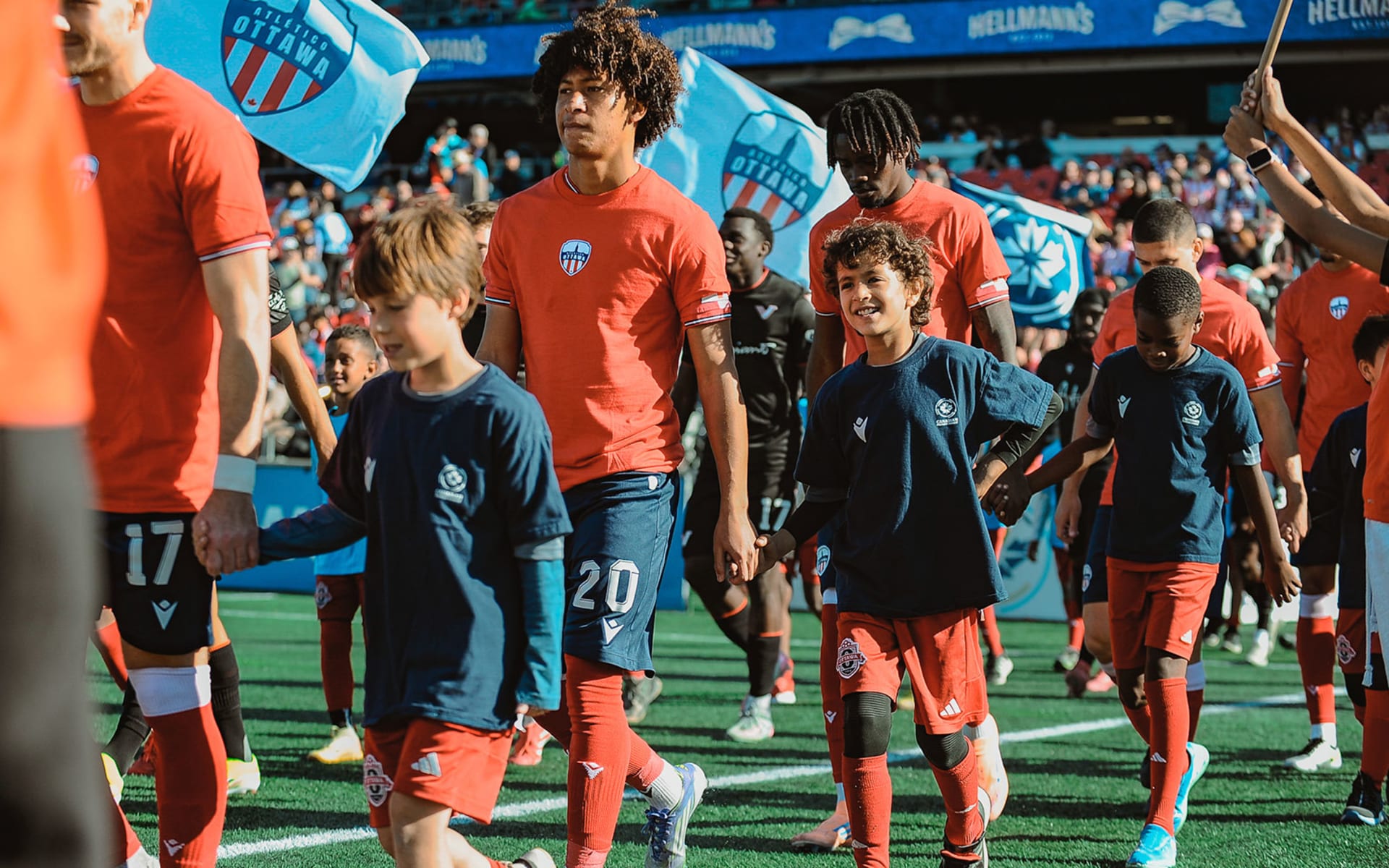 Soccer players walking with young fans